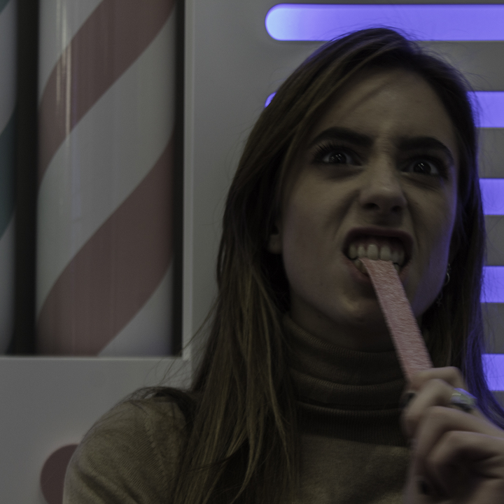 Woman Enjoying a Sweet Treat in a Colorful Candy-Themed Setting. 