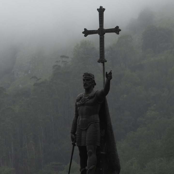  Statue of Don Pelayo, first King of Asturias, standing proudly with a cross in Covadonga, surrounded by misty mountains, evoking historical and cultural significance in Spain.