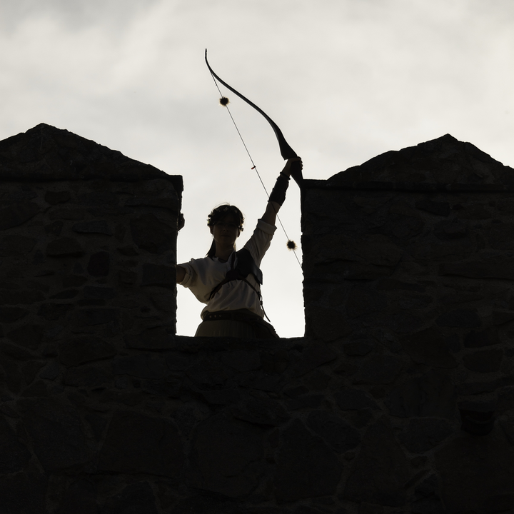  Woman archer raising her bow on the historic rampart walls of Ávila during the Medieval Fair and Market, evoking heritage and tradition. . Medieval Market and Fair at Avila, Spain. September 2025. 