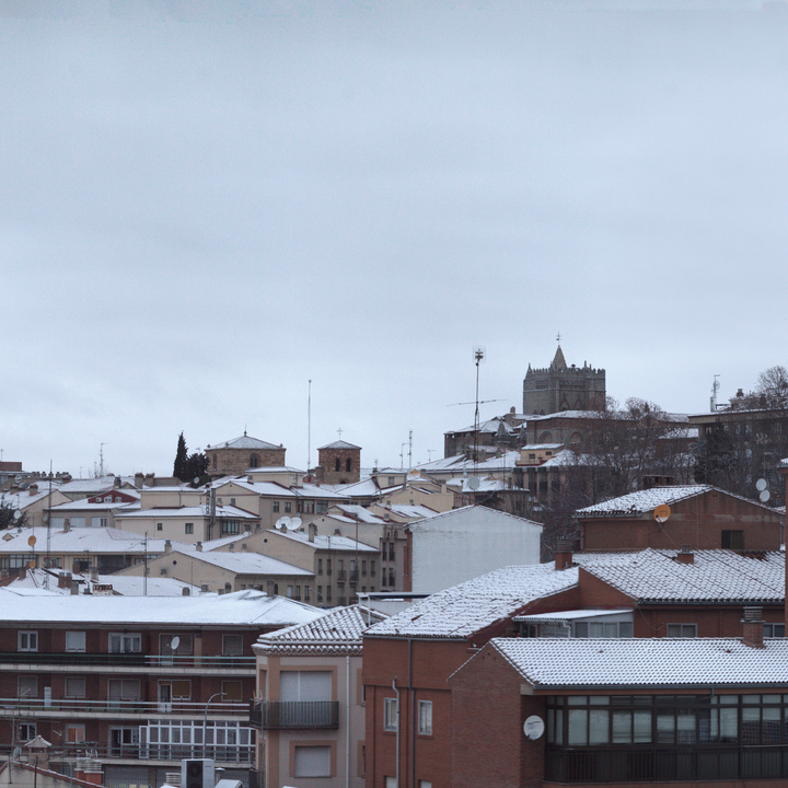  Panoramic winter view of Ávila from the south west, showing snow-covered rooftops, historic church towers and residential buildings, capturing the calm atmosphere of a cold day in a traditional Spanish city. January 2026. 