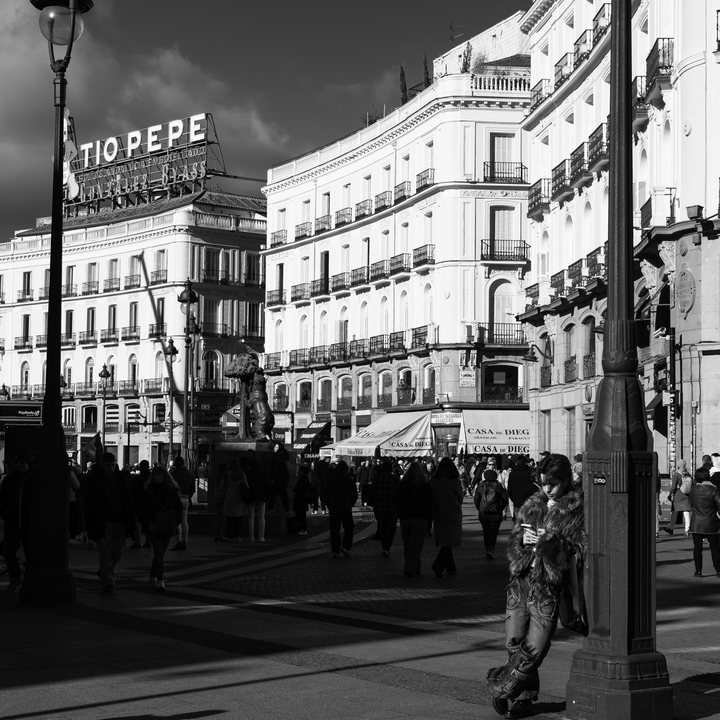 Daily life and historic buildings at Puerta del Sol square under clear winter light.