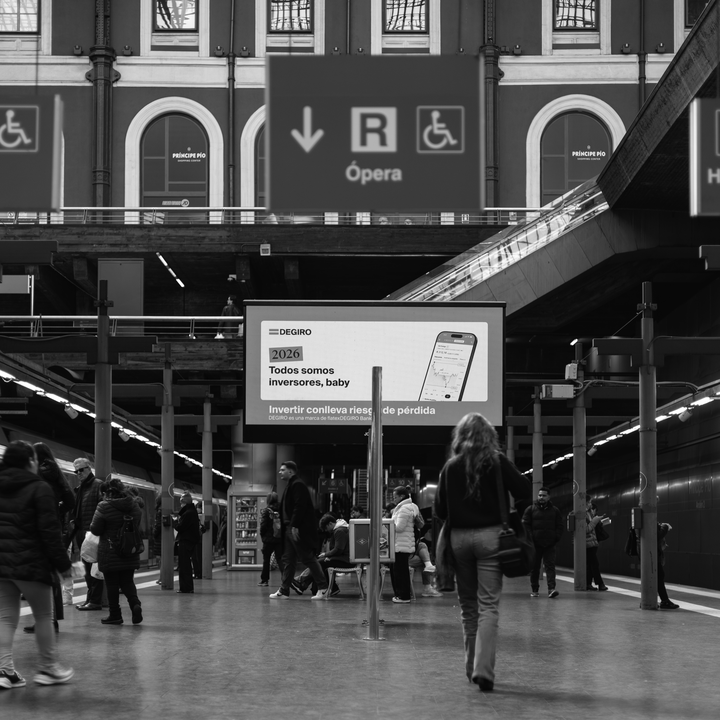 Candid black and white photograph captures a woman in motion blur walking across the platform at the busy Principe Pio Metro Station in Madrid, Spain, Europe.